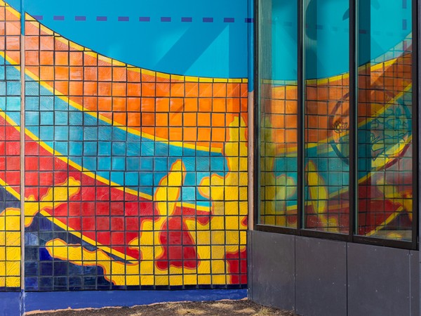 A colorful mural is painted on the exterior of an urban building that says Steel City Squash