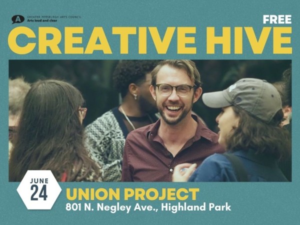 A smiling man looks at the camera while talking to a group inside a busy event space. Creative Hive at Union Project on June 24