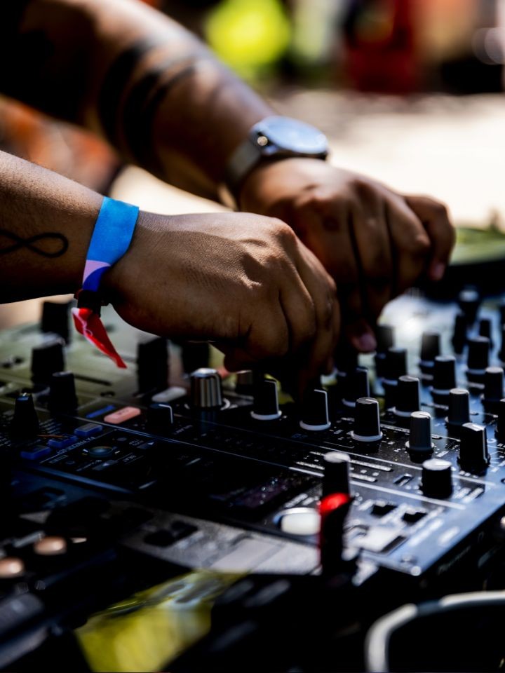 Close-up of Black hands adjusting controls on a music soundboard