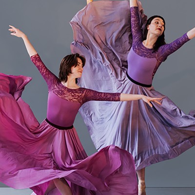 Two dancers pose in flowing purple dresses