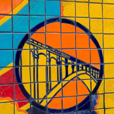 A colorful mural is painted on the exterior of an urban building that says Steel City Squash