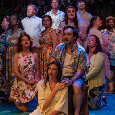 A photo of a group of actors on stage standing in a circle