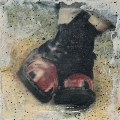 An art piece of feet crossed with black and red shoes on in front of a white, yellow, green, and blue background with black dots