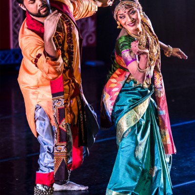 A man and a woman dressed in traditional Indian attire dance on stage