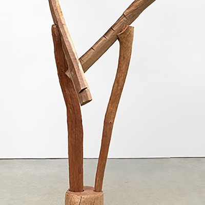 Tall wooden sculpture showing distinct lines attached to a wooden podium