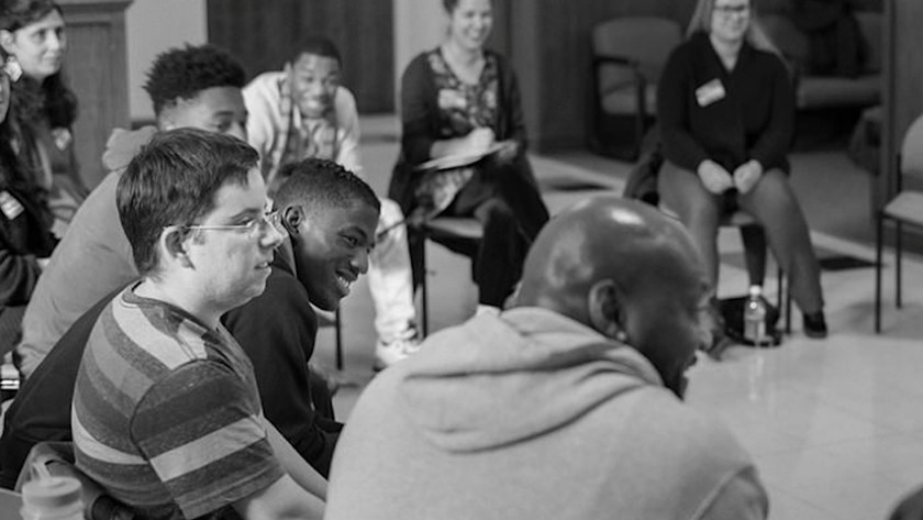 Black-and-white photo of a group of people of different races sitting around in a circle