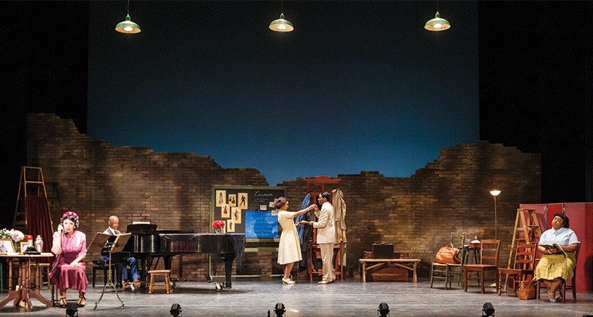 Theater stage showing multiple actors under overhead lights