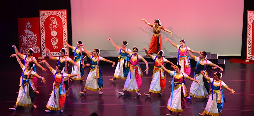 14 women in traditional Indian dresses dance on stage